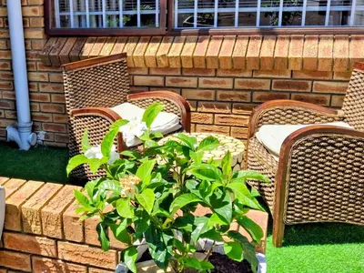 a patio with three wicker chairs and a plant at Olly-Pops Cottage in Tygerberg Hills