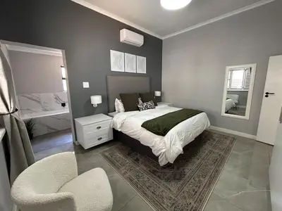 a bedroom with a bed and a chair in it at A home away from home near the beach in Strand