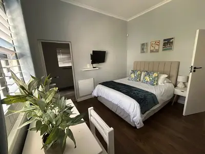 a bedroom with a bed and a table with a plant at A home away from home near the beach in Strand