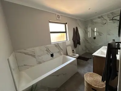 a white bathroom with a tub and a sink at A home away from home near the beach in Strand