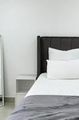 a bed with a black headboard and a white pillow at Flatlet on Circle in Cape Town