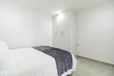 a white bedroom with a bed and white walls at Flatlet on Circle in Cape Town