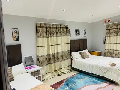 a bedroom with two beds and a tv and curtains at claremont AN guesthouse in Cape Town