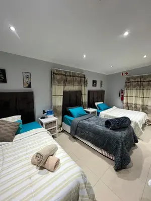 a bedroom with three beds with blue pillows at claremont AN guesthouse in Cape Town