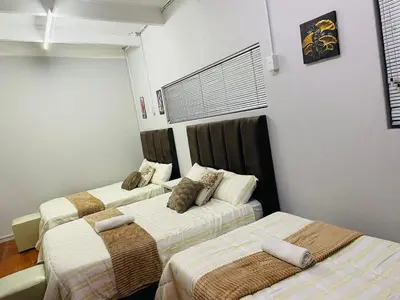 two beds in a room with white walls at claremont AN guesthouse in Cape Town