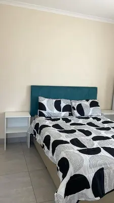 a bed with a black and white comforter and pillows at Delightful Retreat in Parklands,Cape Farms,Cape Town in Cape Town