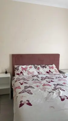 a bedroom with a bed with a pink headboard at Delightful Retreat in Parklands,Cape Farms,Cape Town in Cape Town