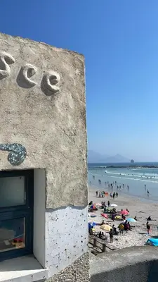 a building on a beach with people on the beach at Delightful Retreat in Parklands,Cape Farms,Cape Town in Cape Town