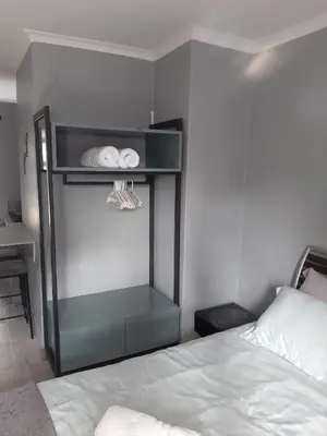 a bedroom with a bed and a shelf with towels at The Pink Flamingo Self Catering Accommodation in Cape Town