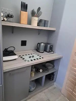 a kitchen with a stove and shelves with utensils at The Pink Flamingo Self Catering Accommodation in Cape Town
