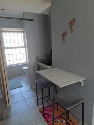 a kitchen with a white table and two stools at The Pink Flamingo Self Catering Accommodation in Cape Town