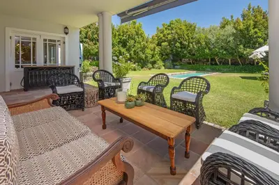 a patio with wicker chairs and a wooden table at Fir Close 3 bedroom in Hermanus