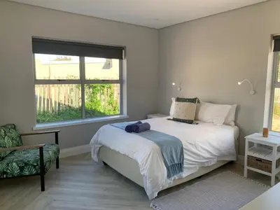 a bedroom with a white bed and a window at Taylah's Hideaway in Bettyʼs Bay