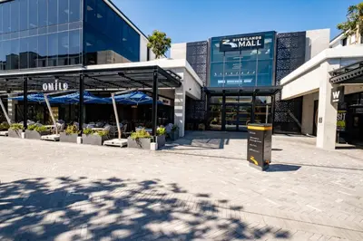 a shopping center with blue umbrellas in front of a building at 729 Riverlands - Lux Studio Apartment in Cape Town