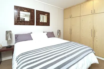 a bedroom with a large white bed with two mirrors at City Vibes and Mountain Highs 2 Bed, 2 Bath Apart