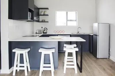 a kitchen with a counter with stools and a refrigerator at Flat in Security Estate - Zomerwind Apartments in Oakdale