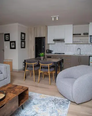 a kitchen and living room with a table and chairs at Cape on Viola in Cape Town