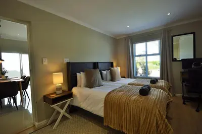 a hotel room with a bed and a desk and a window at Montbleu 3 Bed 3 Bath House in residential security Estate in Stellenbosch