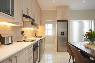 a kitchen with wooden cabinets and a stainless steel refrigerator at Montbleu 3 Bed 3 Bath House in residential security Estate in Stellenbosch