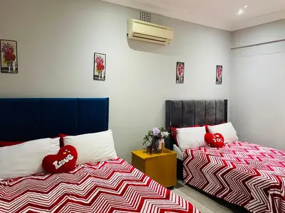 two beds in a room with red pillows on them at Annika`s dormitory in claremont in Cape Town