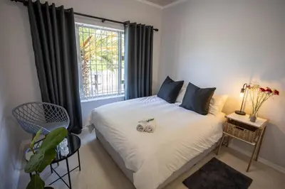 a bedroom with a white bed with a window at The Palm in Kraaifontein