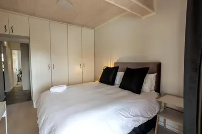 a bedroom with a large white bed with black pillows at The Palm in Kraaifontein