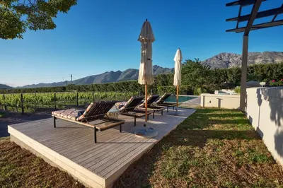 a row of lounge chairs and umbrellas on a wooden deck at The Manor House at Colmant in Franschhoek