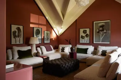 a living room with red walls and white couches at The Manor House at Colmant in Franschhoek