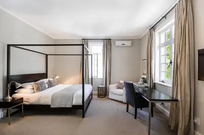 a bedroom with a canopy bed and a desk at River Manor Boutique Hotel by The Living Journey Collection in Stellenbosch