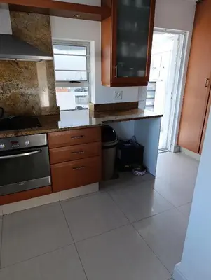 a kitchen with wooden cabinets and a stove top oven at Ascot manor in Cape Town