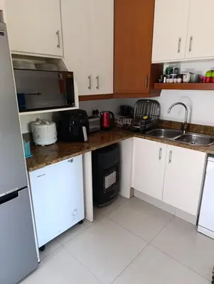 a kitchen with white cabinets and a sink and a refrigerator at Ascot manor in Cape Town