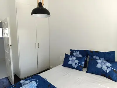 a bedroom with a bed with blue and white pillows at Ascot manor in Cape Town