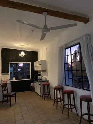 a kitchen with bar stools and a ceiling fan at The Barn, at Glenora Avenue in Somerset West