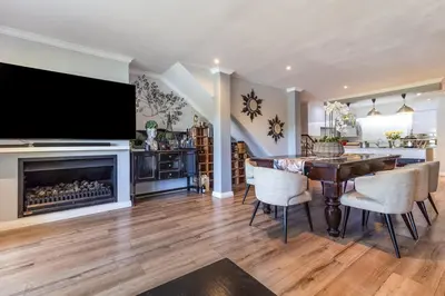 a living room with a dining table and a fireplace at Luxury Lakeside Lodge at Jack Nicklaus Golf Estate in Simondium