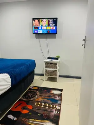 a bedroom with a bed and a tv on the wall at A guesthouse & Dormitory beds Claremont in Cape Town