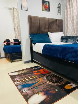 a bedroom with a bed and a rug on the floor at A guesthouse & Dormitory beds Claremont in Cape Town