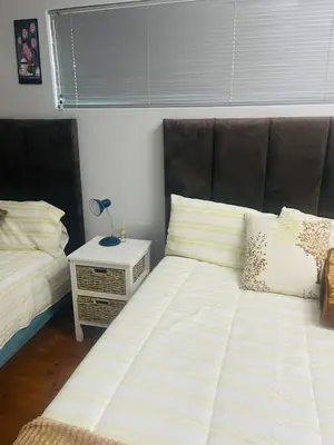 a bedroom with two beds and a lamp on a night stand at A guesthouse & Dormitory beds Claremont in Cape Town