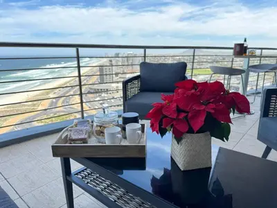 a balcony with a table with a vase of red flowers at Blu Horizon in Cape Town
