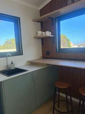 a kitchen with two windows and a sink and two stools at Logans place in Hermanus