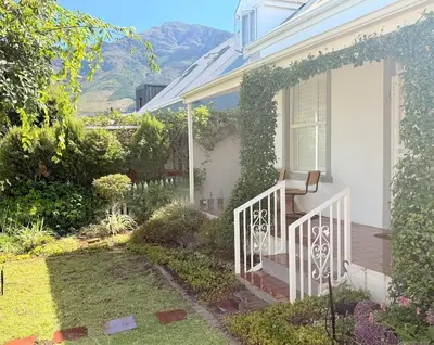 a white house with a bench on the front porch at Crescent House in Franschhoek