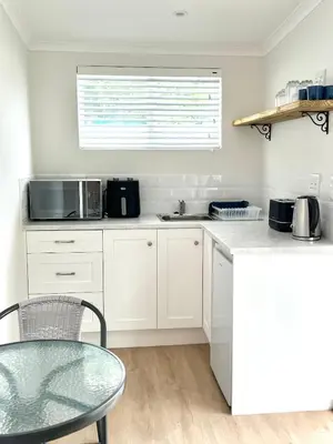 a white kitchen with a table and a microwave at Mountain View Voëlklip One Bedroom in Hermanus