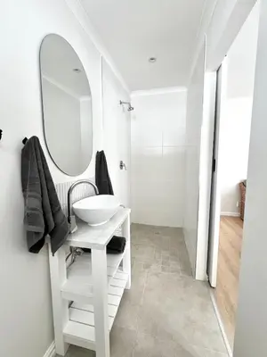 a white bathroom with a sink and a mirror at Mountain View Voëlklip One Bedroom in Hermanus