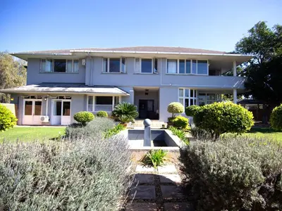 a large white house with bushes in front of it at The Boston Guest House in Bellville
