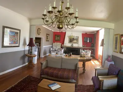 a living room with a table and a chandelier at The Boston Guest House in Bellville