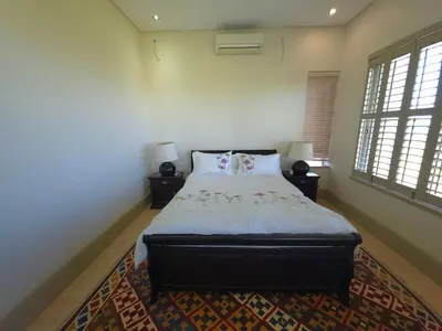 a bedroom with a large bed and two windows at Beachfront Golf Estate Escape in Strand in Strand