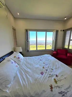 a bedroom with a large bed and a red chair at Beachfront Golf Estate Escape in Strand in Strand