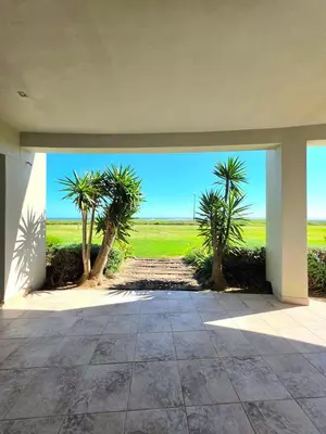 an empty patio with palm trees in the distance at Beachfront Golf Estate Escape in Strand in Strand