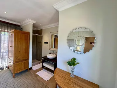 a bathroom with a table and a mirror on the wall at Quiet Business Stay with Stunning Pool in Welgemoed