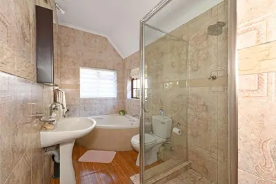 a bathroom with a tub and a toilet and a sink at Unique Thatch Home in Champagne area in Pinelands in Cape Town