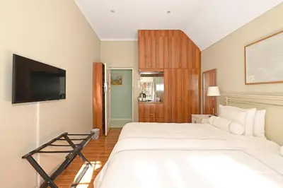 a bedroom with a large white bed and a flat screen tv at Unique Thatch Home in Champagne area in Pinelands in Cape Town